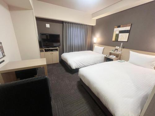 a hotel room with two beds and a television at ​Hotel Route-Inn Ube​ in Ube