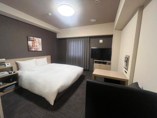 a hotel room with a bed and a television at ​Hotel Route-Inn Ube​ in Ube
