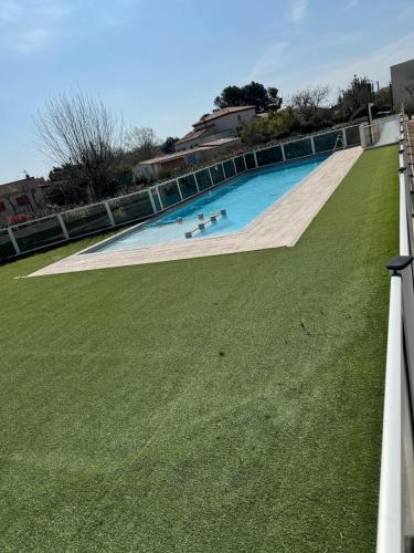 une grande piscine avec une pelouse verdoyante dans l'établissement Villa proche plage, à Sérignan