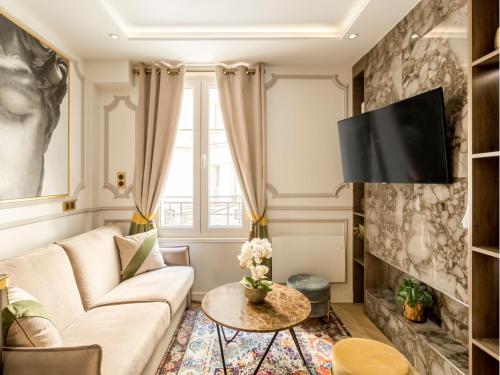 Una sala de estar con un sofá y un televisor. en Merveil - Luxury Suite - Notre Dame - Monge, en París