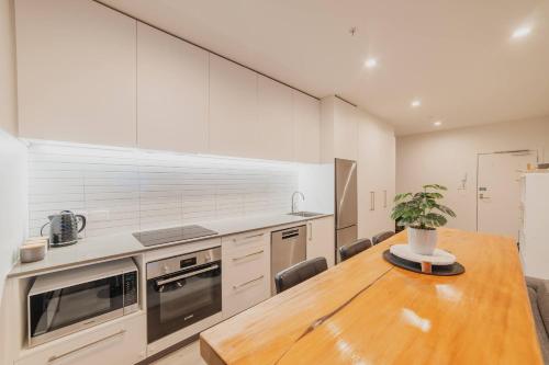 a kitchen with a wooden table and a counter top at Tuam St Stay - 1BR with Balcony Bath in Christchurch