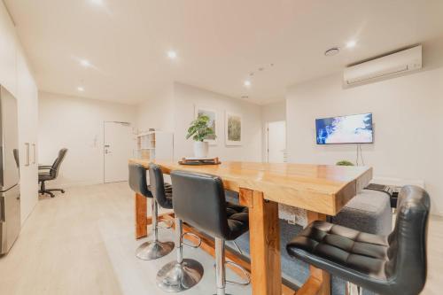 a dining room with a wooden table and black chairs at Tuam St Stay - 1BR with Balcony Bath in Christchurch