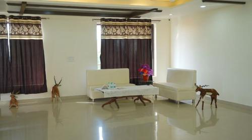 a living room with two chairs and a table and deer statues at Pink Park by Panache Hotels in Bīr