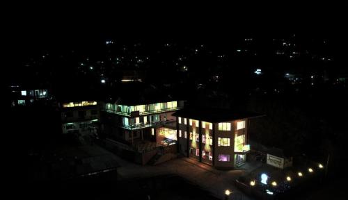 a lit up building at night with lights at Pink Park by Panache Hotels in Bīr