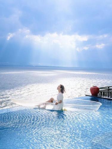 a woman sitting on a surfboard in the water at Dali Mermaid Seascape Resort Hotel in Dali
