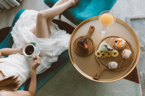a woman in a white dress holding a cup of coffee and a plate of food at Dali Mermaid Seascape Resort Hotel in Dali