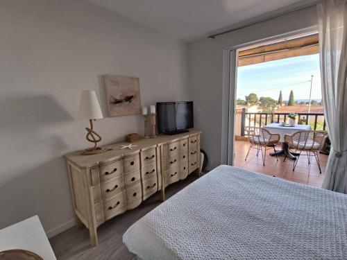 une chambre avec un lit et une télévision et un balcon dans l'établissement Bleu d' Azur, 4 pers vue mer, gare et coeur de ville 20mn à pied, à Saint-Raphaël