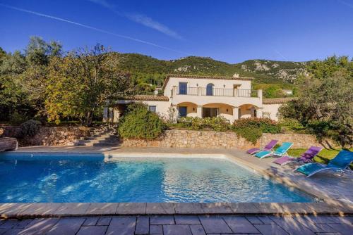 une maison avec une piscine et deux chaises longues dans l'établissement Villa Cramond - avec Piscine pour 8 Pers - Tourrettes-sur-Loup, à Tourrettes-sur-Loup