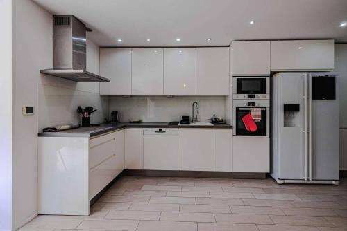  La cuisine est équipée de placards blancs et d'un réfrigérateur. dans l'établissement Marina Rey - Apt pour 4 à 400m des plages Côte d'Azur, à Villeneuve-Loubet