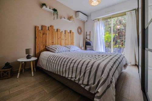 une chambre avec un lit avec une tête de lit en bois et une fenêtre dans l'établissement Marina Rey - Apt pour 4 à 400m des plages Côte d'Azur, à Villeneuve-Loubet