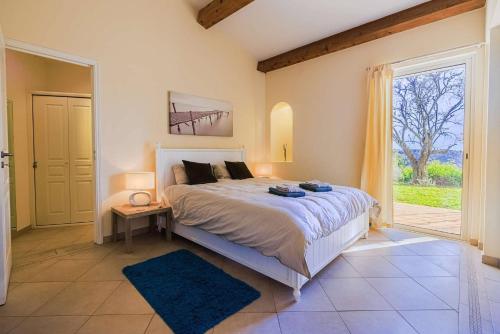 une chambre avec un grand lit et une grande fenêtre dans l'établissement Villa Cramond - avec Piscine pour 8 Pers - Tourrettes-sur-Loup, à Tourrettes-sur-Loup