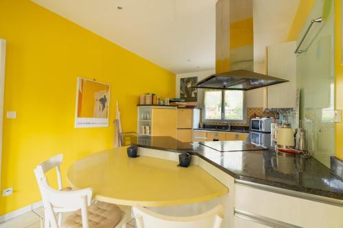 une cuisine avec une table et un mur jaune dans l'établissement Villa spacieuse au pyla avec piscine et jardin, à La Teste-de-Buch