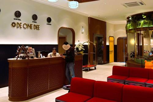 a man standing at a counter in a hotel lobby at Hotel De One Dee in Ban Phaet
