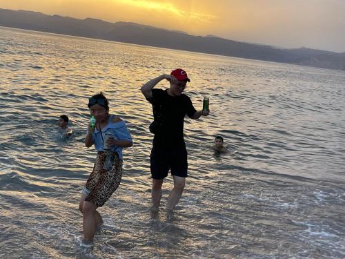 two people standing in the water drinking beer at Pizza Street Hostel in Aqaba
