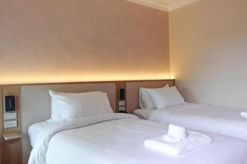 two beds in a room with white sheets and pillows at Hotel De One Dee in Ban Phaet