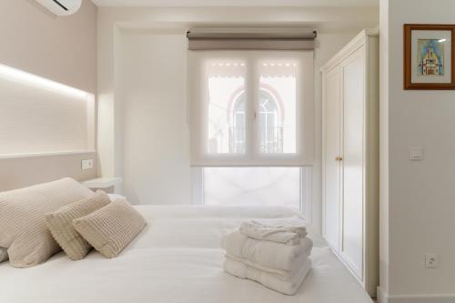 a white bedroom with a bed with towels on it at Cala Sol - few steps from the beach in La Cala de Mijas