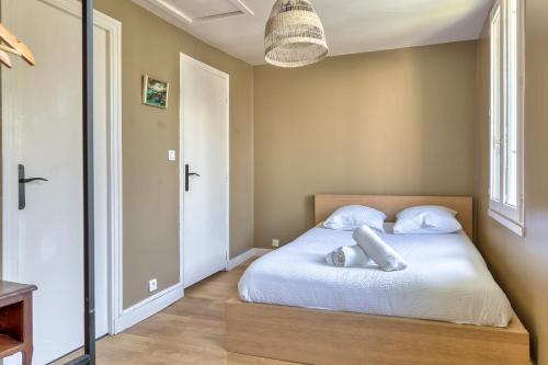 une chambre avec un lit avec des draps blancs et des oreillers dans l'établissement Daoud, charmante maison de ville avec jardin et place stationnement, à Rouen