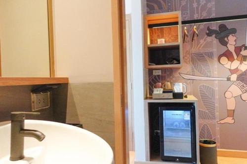 a bathroom with a sink and a picture of a woman at Hotel De One Dee in Ban Phaet