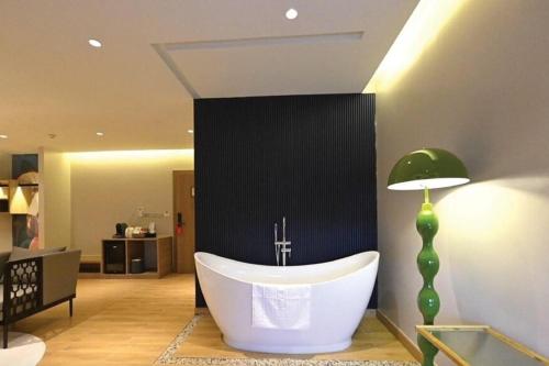 a large bath tub in a room with a lamp at Hotel De One Dee in Ban Phaet