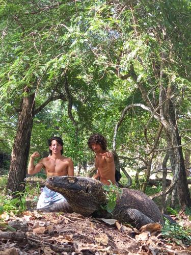 two boys are sitting next to a large alligator at Komodo Homestay in Komodo