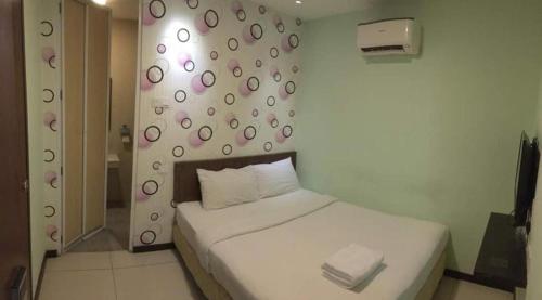 a bedroom with a white bed with a wall with polka dots at Casa Hotel near KLIA 1 in Sepang