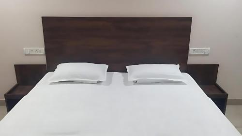 Una cama blanca grande con dos almohadas encima. en Grand Darbar, en Bānda