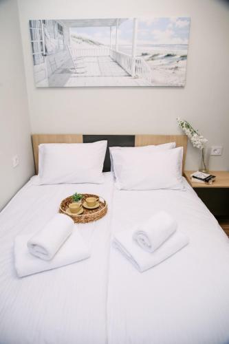 a white bed with two white pillows and a tray with a plate at POOL RESORT- Vila Lena- Apartman 2 in Vrdnik