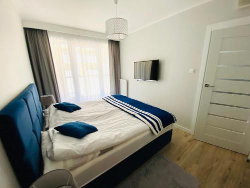 une chambre avec un lit avec des oreillers bleus dessus dans l'établissement APARTAMENTY SPA Kasprowicza 20 Basen Parking Wi-Fi, à Kołobrzeg