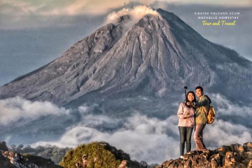 a man and woman standing on top of a mountain at Nachelle Homestay in Berastagi