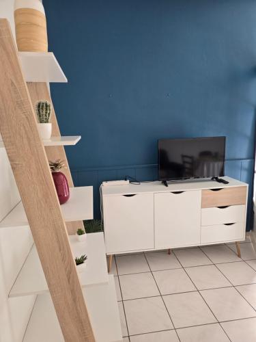 Il comprend un salon doté d'une armoire blanche et d'une télévision. dans l'établissement Appartement rez de jardin avec terrasse privative, à La Bourboule