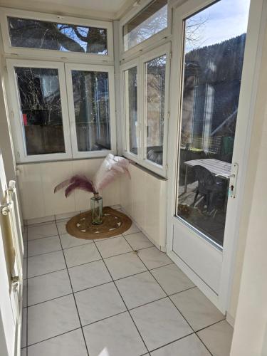 - une véranda avec des fenêtres et une table dans l'établissement Appartement rez de jardin avec terrasse privative, à La Bourboule