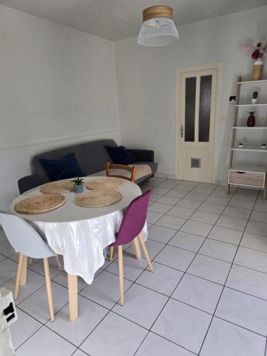 un salon avec une table, des chaises et un canapé dans l'établissement Appartement rez de jardin avec terrasse privative, à La Bourboule