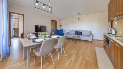 een keuken en een woonkamer met een tafel en stoelen bij Rozewie, Sun & Snow in Jastrzębia Góra