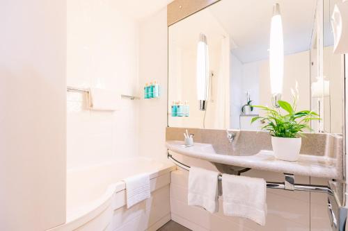 a bathroom with two sinks and a tub and a mirror at Novotel Venezia Mestre Castellana in Mestre
