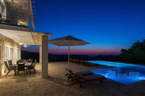 a patio with a table and an umbrella next to a pool at Villa Sunset, stunning villa rental in Corfu by PosarelliVillas in Perítheia