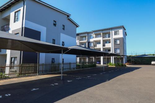 a parking lot with umbrellas in front of a building at Bliss Ballito by First Private Stays in Ballito