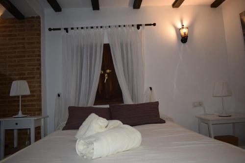 una camera da letto con un letto con lenzuola bianche e una finestra di Nest of love in Seville, Casa el Pocito 1 a Peñaflor