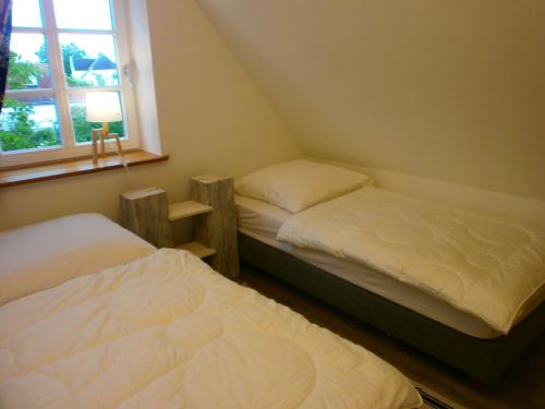 two twin beds in a room with a window at App Nixe mit WLAN und Kamin Haustiere Willkommen in Börgerende-Rethwisch