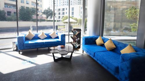 a living room with two blue couches and a large window at Signature Hotel Apartments and Spa in Dubai
