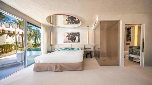 a bedroom with a white bed and a large window at Destino Five Ibiza - 5-Star Grand Luxe Resort in Talamanca