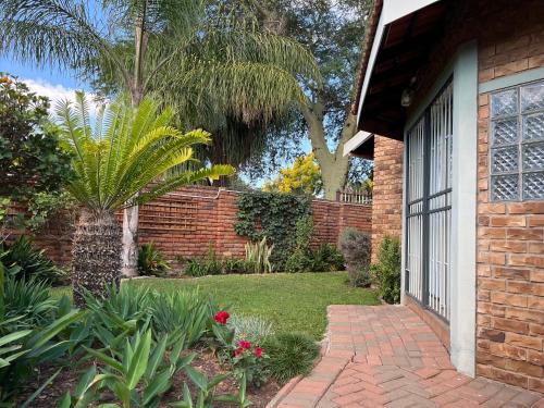 a brick house with a brick walkway next to a garden at Bougain Villa Guest House in Polokwane