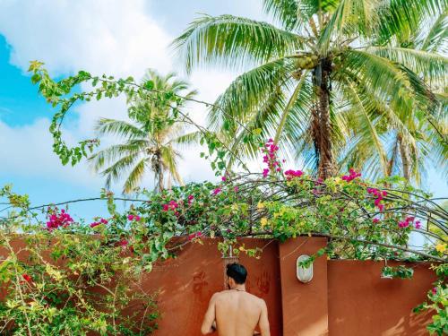 a man standing in front of a wall with flowers at Shanuo Beach Bungalows in Michamvi
