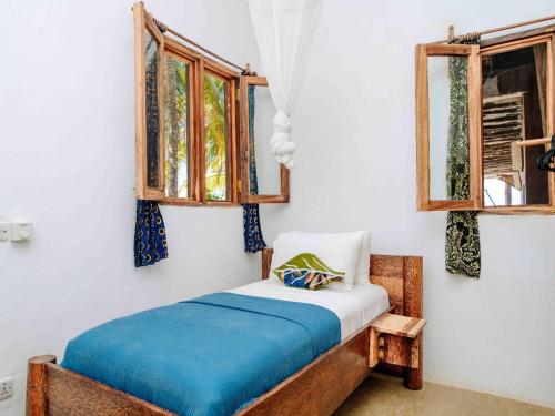 a bedroom with a bed and two windows at Shanuo Beach Bungalows in Michamvi
