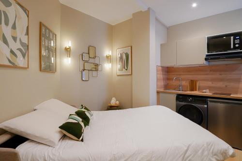 Cet appartement comprend une chambre avec un lit blanc et une cuisine. dans l'établissement Duplex climatisé - Grands Boulevards, à Paris