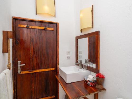 a bathroom with a sink and a wooden door at Shanuo Beach Bungalows in Michamvi