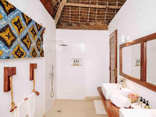 a bathroom with a sink and a shower and a mirror at Shanuo Beach Bungalows in Michamvi