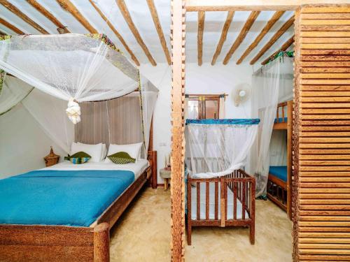 a bedroom with a canopy bed and a chair at Shanuo Beach Bungalows in Michamvi