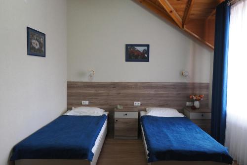 two beds in a room with blue sheets at Asia Hotel in Bishkek