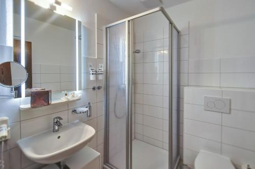 a white bathroom with a shower and a sink at Hotel Sonneninsel Fehmarn in Fehmarn