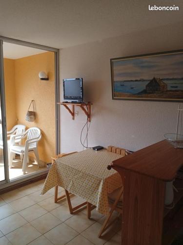 un salon avec une table et une télévision dans l'établissement Location de vacances bord de mer Gruissan, à Gruissan